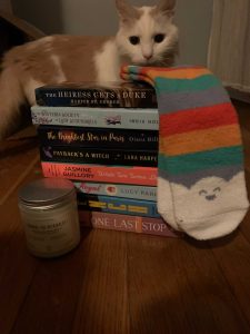 A white and orange fluffy cat peering over a stack of books