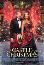 Brooke shields and Cary Elwes in front of a holiday lit castle she is wearing a plaid gown and he is wearing a formal jacket kilt and sporran