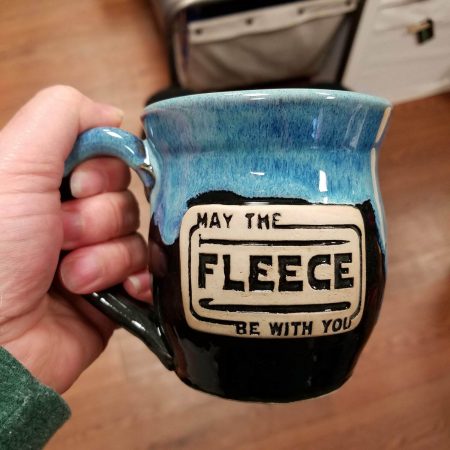 A blue and black mug that says may the fleece be with you