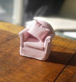 A pink fabric easy chair with a matching pink pillow
