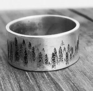 A close up of a silver ring with fir trees stamped on the outside 