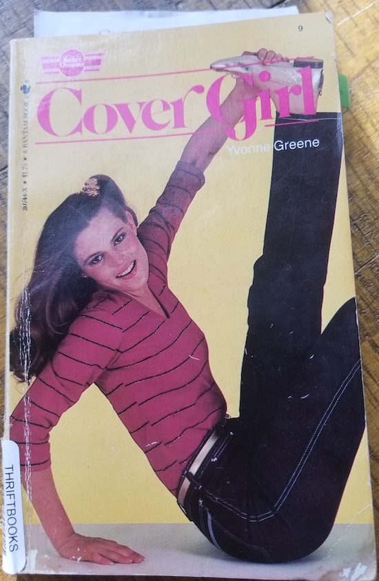 A photograph of a book with a model in a red striped shirt holding her foot flexed above her she's wearing metallic gold shoes, belt and scrunchie too