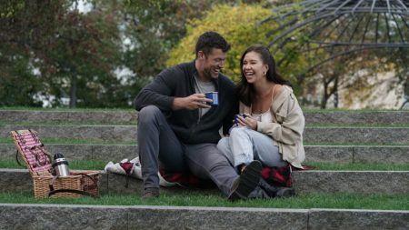 Gabby and Clayton sit on stone steps and drink coffee