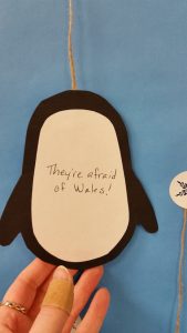 A close up of the back of a paper penguin that reads They're afraid of wales!