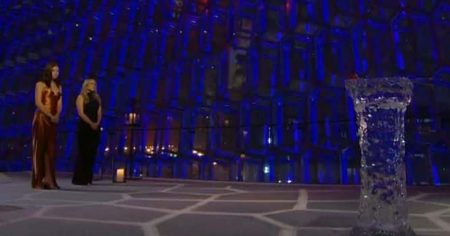 Gabby and Rachel stand in a giant blue hall with what looks like a pedestal carved of ice