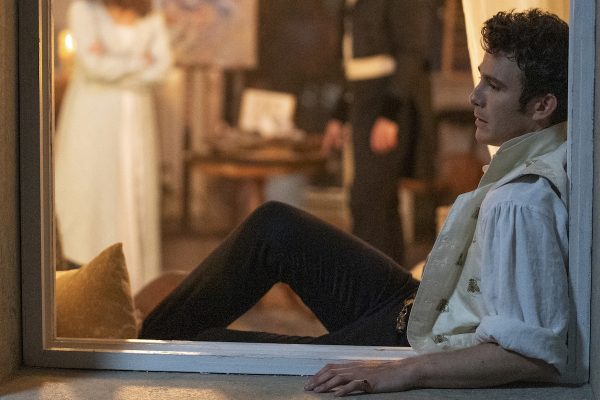 Benedict lounges in a windowsill at night, with a woman in white behind him