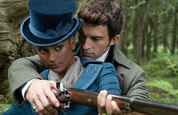 Kate and Anthony practice shooting. Kate is in a blue long riding coat iwth an embroidered collar and a jaunty blue top hat at an angle. Anthony is staring at her and seems transfixed by everything about her including her ear