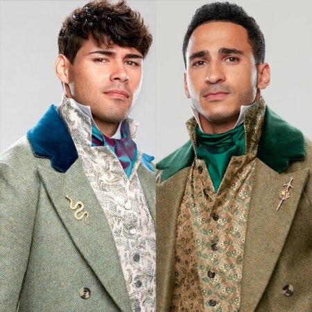 Two men in formal jackets, Judge on the left is in pale green with a blue velvet collar and cravat while his waistcoat is embroidered in green on a cream background. Hatem on the right is in darker green with an embroidered waistcoat, and a green velvet collar and green ascot they're each wearing pins on their lapel, too and it's weird. Judge has a snake and Hatem has a sword through some kind of rosette they are really going all in on costuming I bet that department had a lot of fun