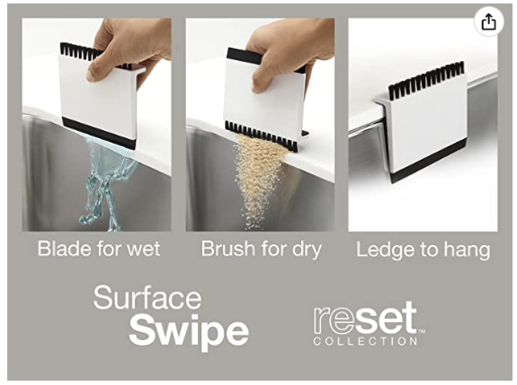 An image of a platic kitchen tool that has a rubber wiping edge on one side, a brush on the other, and a ledge to hang it off the sink