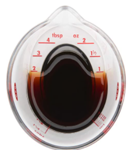 overhead shot of a miniature measuring cup that holds ounces, ML, and holds a total of a quarter cup