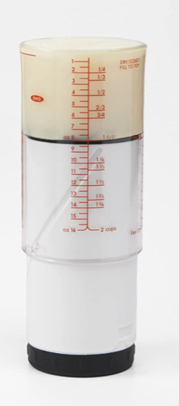An oxo plastic adjustable measuring cup with some thick ingredient maybe sour cream in the top 