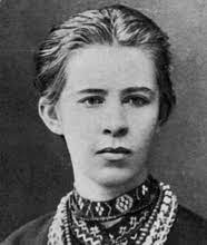 black and white close up photo of Lesya's face She has a serious expression, her hair is pulled back and she appears to be wearing a sweater and scarf 