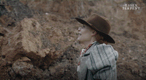 Cors in a floppy hat chips away at a local cliff for fossils