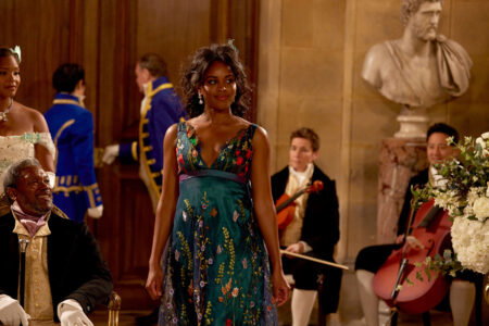 Nicole glows in an emerald green sleeveless dress embroidered with colorful flowers.