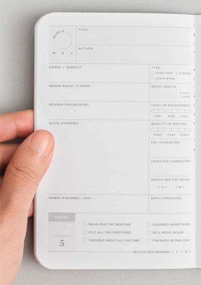 A close up of the interior of the book passport with a White person's hand holding open the pages - it's less than hand-sized so it's small, and there's a lot of detail like title, author, but also what number book this is - I guess reading order? - genre, subject, origin, reason, quick synopsis, and rating which is broken down with additional check boxes like read past my bedtime, felt all the emotions, thought about all the time, learned something, will read again, finished in one day, would recommend etc 