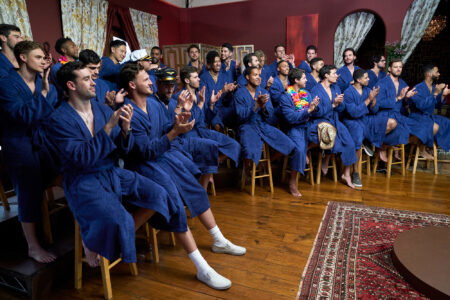 The guys sit in blue bathrobes waiting to show off their swimsuits.