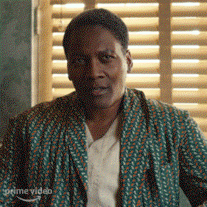 Bertie, played by Lea Robinson, in a still from the show, wearing a green printed robe and a white shirt underneath. 