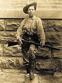 photo of Lillie in men's clothing with rifle