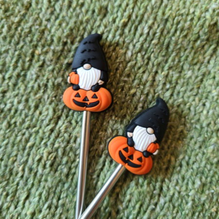Stitch stoppers shaped like gnomes sitting on pumpkins. The gnomes are dressed in black