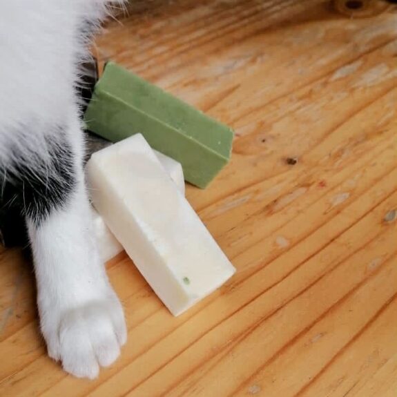 Stack of soaps being sat upon by a black and white cat and only her paw is visible. This is Agatha.