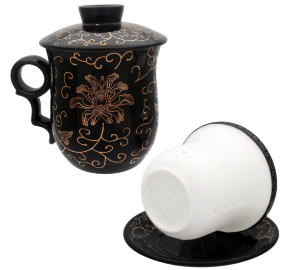 A black teacup with a gold filigree pattern on the outside, with a lid, an infuser that sits inside the teacup, and a saucer beneath