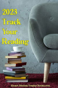 2023 Track Your Reading with an image of a grey chair and a stack of books on the floor with a teacup on top