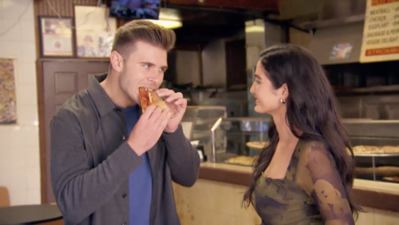 Zach eats a piece of pizza