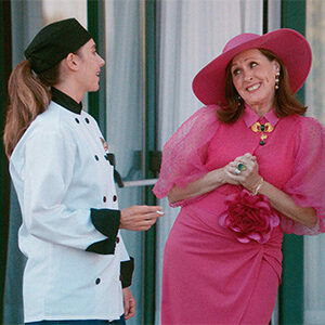 Amber, in chef's coat, talking to Deb, played by Molly Shannon, in a pink poufy dress