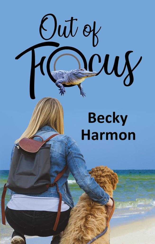 Out of Focus by Becky Harmon. A blonde woman wearing dark jeans, a jean jacket, and gray canvas backpack, squats on the beach next to her dog. The dog has curly tan hair. The title is above them in the blue sky over the water and an alligator is emerging from the O in the word "focus."