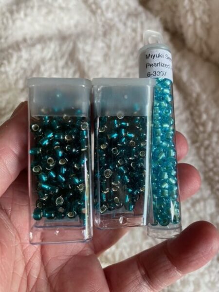 Two boxes of teal beads and one of turquoise beads.