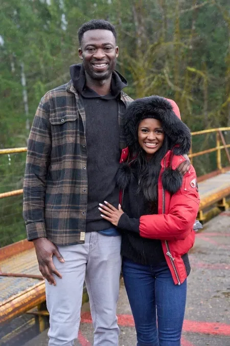 Charity and Dotun pose for a photo. She's wearing a red parka