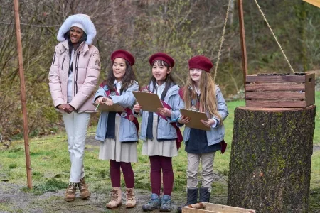 Charity stands next to the scouts who are in blue jackets, red beanies, and red sashes and look adorable and also incredibly smart and competent