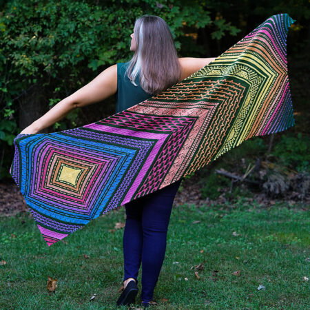 A rectangular shawl with bright colors contrasted against black. There's a lot of colorwork and it's very vivid