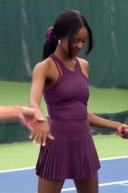 Charity wears a plum colored tennis dress with a pleated skirt. It has a tank style front almost like a racer back but in front and is so cute