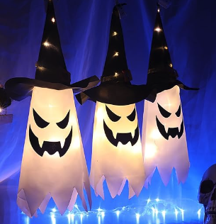Three glowing ghosts with menacing jack o lantern faces and black witch hats that hang from a tree or a railing and light up 