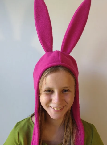 A young White girl with adorable freckles wearing a pink fleece bunny hat similar to the one Louise wears on Bob's Burgers 