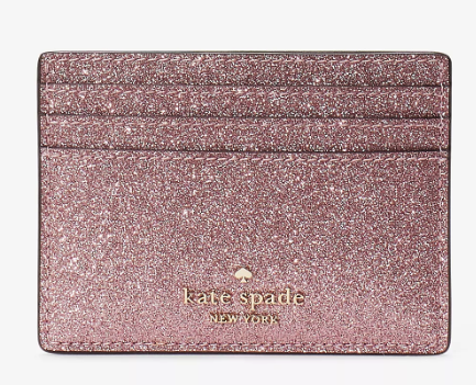 A pink glittery small wallet with three card slots and gold stamping that reads kate spade new york