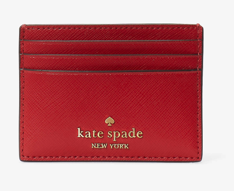A slim leather card holder with three slots for cards in red leather with kate spade new york in gold