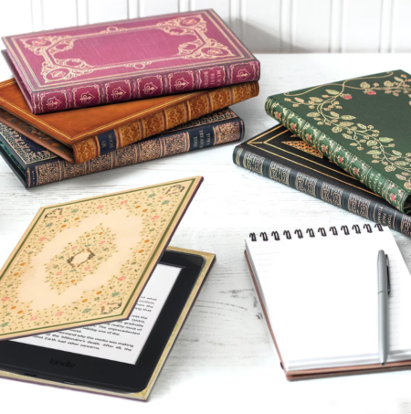 A collection of the ereader covers in pink, tan, blue, black, grene, and cream with different designs. the green has strawberries embossed on it while the others have geometric shapes and borders