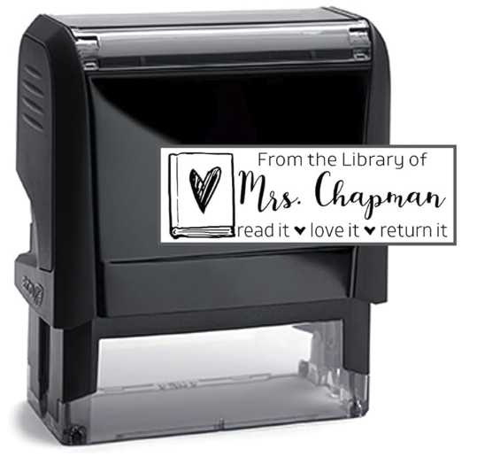 A black plastic self inking stamp that reads FROM THE LIBRARY OF MRS CHAPMAN read it love it return it with a heart scribbed on the top of a book over to the left