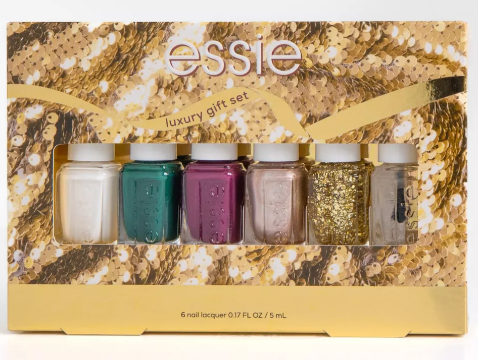 A six piece nail polish set with top coat, white, dark green, dark red, pearly pink, and gold glitter topper.