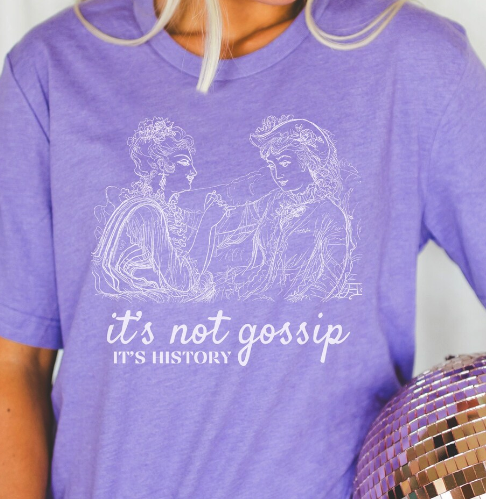 A purple shirt with "it's not gossip if it's history" and a line drawing of two women in historical dress chatting away 