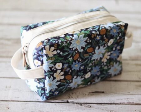 A rectangular quilted bag with a dark blue background and a winter floral design.
