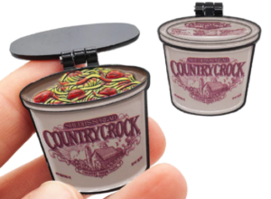 An enamel pin of a tub of Country Crock spread with a hinged lid that opens to show leftover spaghetti