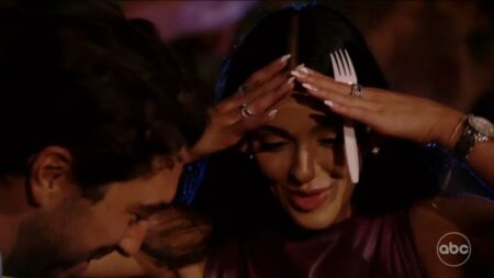 Lauren has her hands on her head while holding a plastic fork.