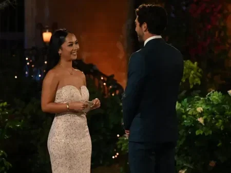 Lea stands in front of Joey holding her card.