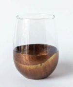 A stemless glass wineglass with the lower half dipped in bronze leaving a metal coating with a wavy effect