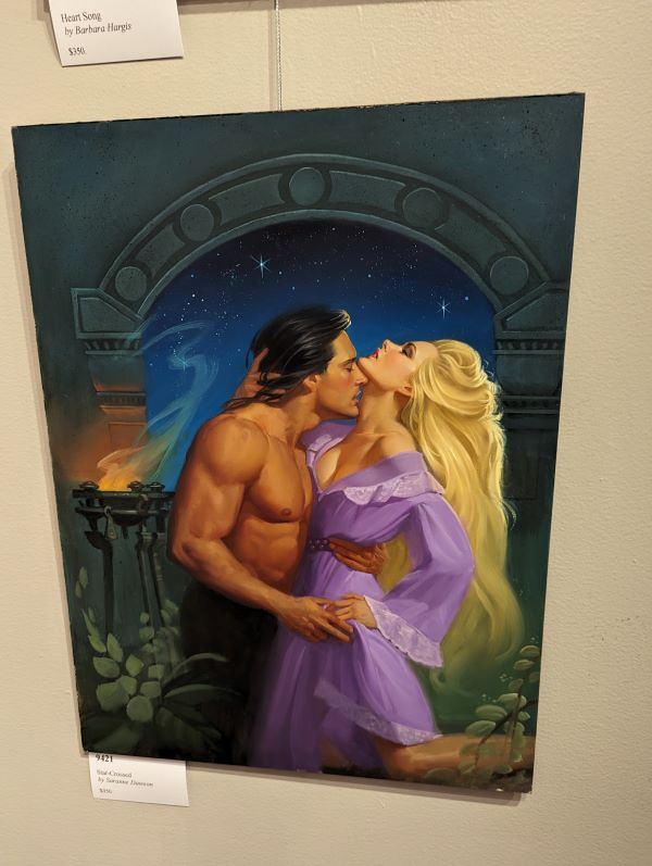 John DeSalvo, again with a mullet, and white woman with light blonde hair and a purple gown embrace against a domed portal with a deep blue sky behind them