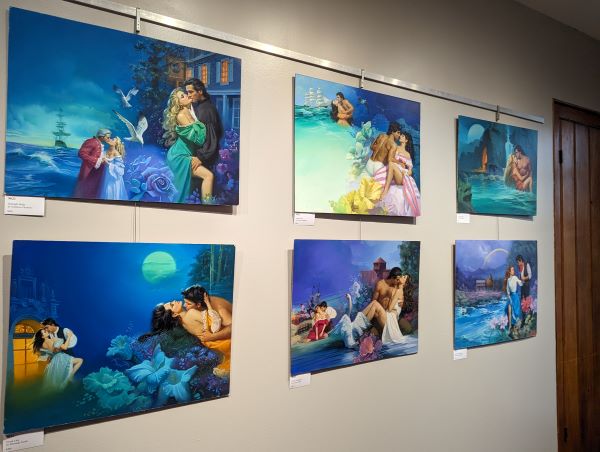 A series of six oil paintings by John ennis in various shades of blue, featuring women in various stages of undress from gowns of yellow, green and gold, with oceans and giant flowers behind them. The overall effect is a lush and glowing blue collection