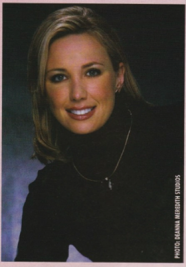 Kresley Cole, a white woman with straight blonde hair to her shoulders wears a black turtleneck and gold necklace, and she's leaning to one side resting on her right elbow 